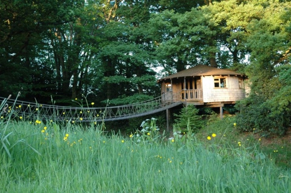 A rope bridge over a pond leads to the Bensfield Treehouse, equipped with a full kitchen and bathroom. | www.facebook.com/SmallHouseBliss