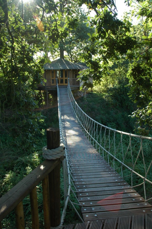 A rope bridge over a pond leads to the Bensfield Treehouse, equipped with a full kitchen and bathroom. | www.facebook.com/SmallHouseBliss