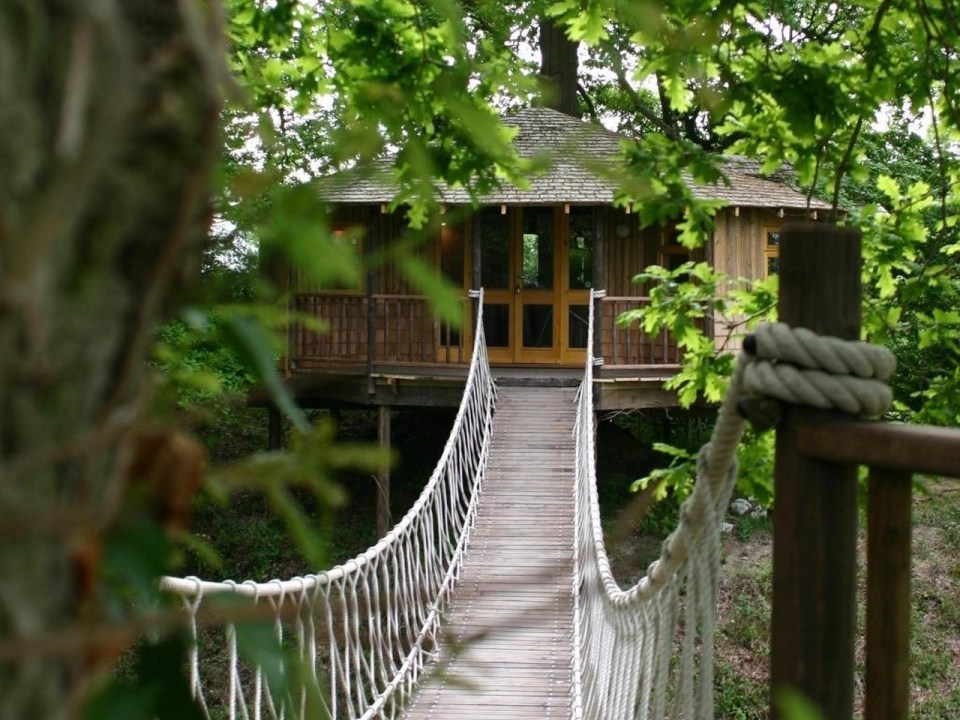 A rope bridge over a pond leads to the Bensfield Treehouse, equipped with a full kitchen and bathroom. | www.facebook.com/SmallHouseBliss