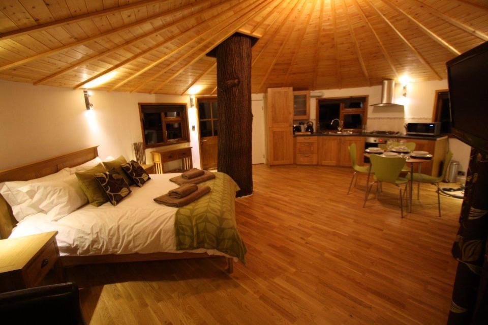 A rope bridge over a pond leads to the Bensfield Treehouse, equipped with a full kitchen and bathroom. | www.facebook.com/SmallHouseBliss