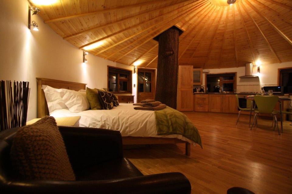 A rope bridge over a pond leads to the Bensfield Treehouse, equipped with a full kitchen and bathroom. | www.facebook.com/SmallHouseBliss