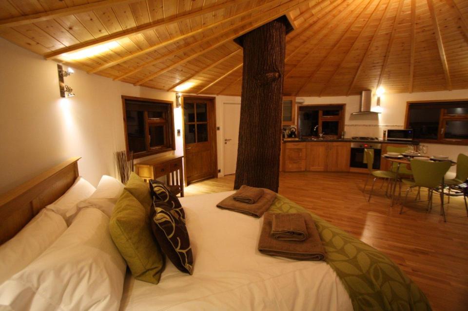 A rope bridge over a pond leads to the Bensfield Treehouse, equipped with a full kitchen and bathroom. | www.facebook.com/SmallHouseBliss