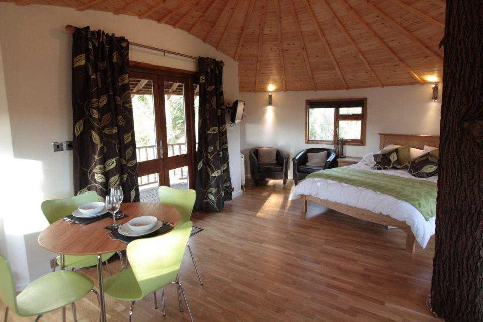 A rope bridge over a pond leads to the Bensfield Treehouse, equipped with a full kitchen and bathroom. | www.facebook.com/SmallHouseBliss