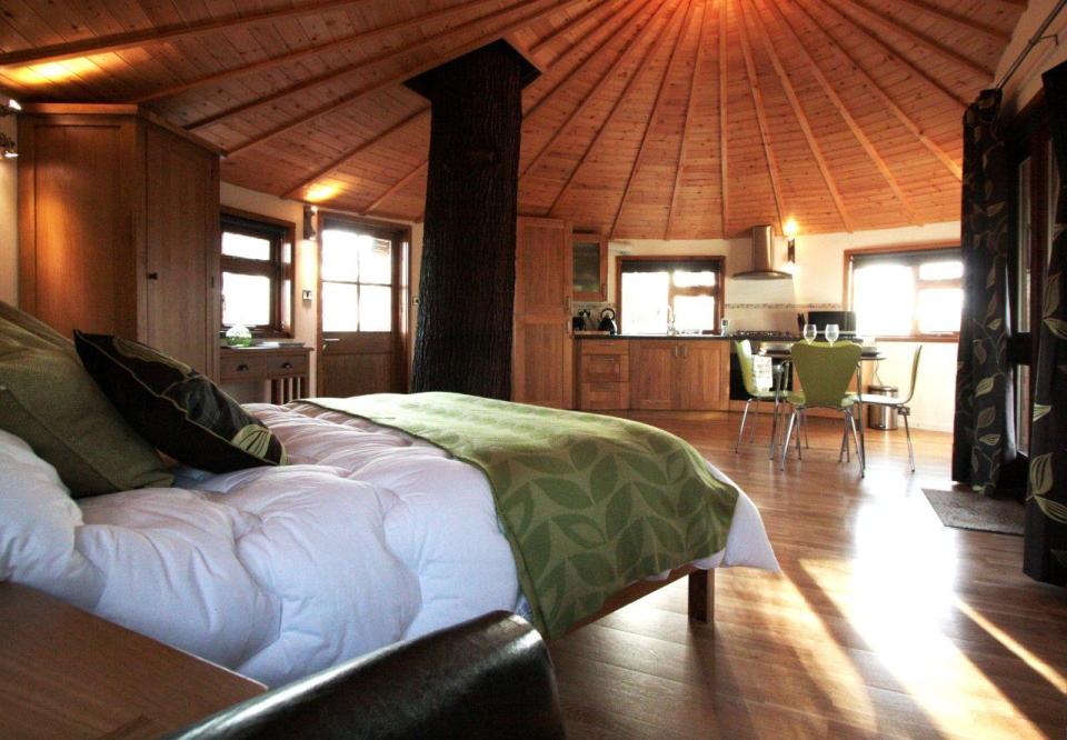 A rope bridge over a pond leads to the Bensfield Treehouse, equipped with a full kitchen and bathroom. | www.facebook.com/SmallHouseBliss