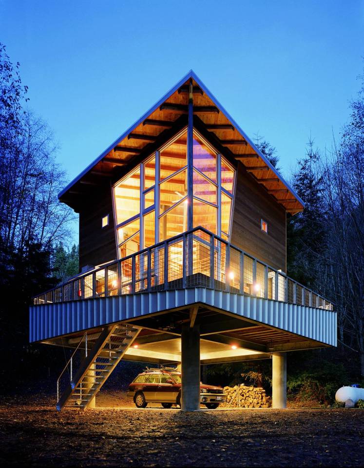 This elevated cabin features a double-height corner window. It has 800 sq ft and a pair of lofts for sleeping. | www.facebook.com/SmallHouseBliss