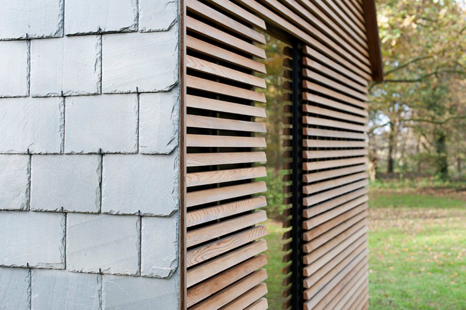 This tiny vacation cottage opens to the garden with a wall of shutters. Built-in cabinetry houses the bathroom, fireplace and kitchen. | www.facebook.com/SmallHouseBliss