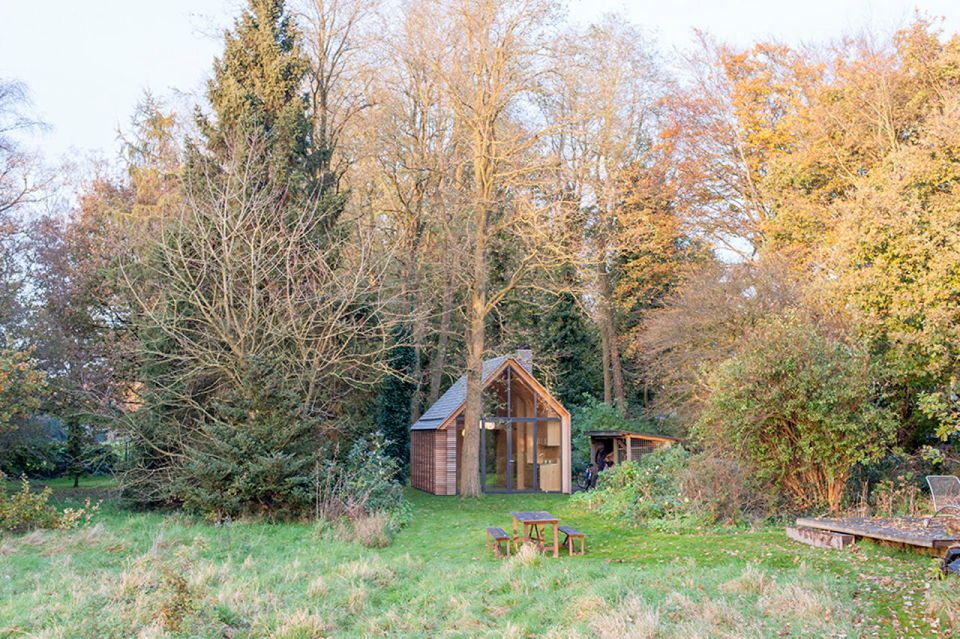 This tiny vacation cottage opens to the garden with a wall of shutters. Built-in cabinetry houses the bathroom, fireplace and kitchen. | www.facebook.com/SmallHouseBliss
