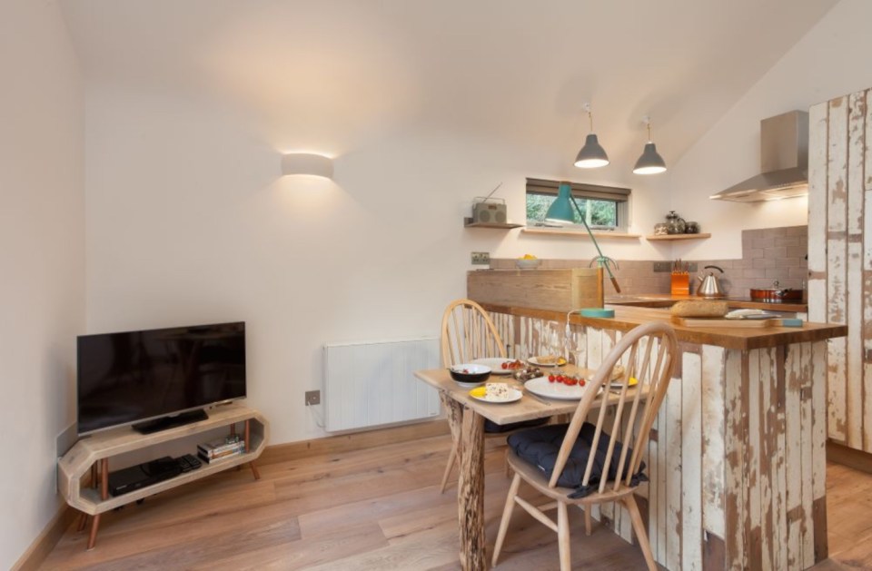 The Birdhouse Treehouse, a tiny wooden cottage in a woodland clearing. It has an open floor plan with a semi-separate bedroom space. | www.facebook.com/SmallHouseBliss