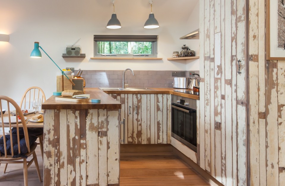 The Birdhouse Treehouse, a tiny wooden cottage in a woodland clearing. It has an open floor plan with a semi-separate bedroom space. | www.facebook.com/SmallHouseBliss