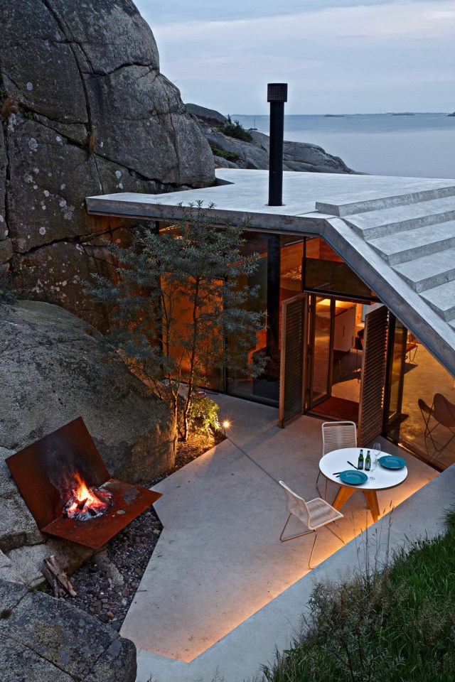 Half-hidden by dense vegetation, this modern cabin is tucked into a rocky Norwegian coastline. It is a 323 sq ft studio design with a sleeping loft suspended from the ceiling. | www.facebook.com/SmallHouseBliss