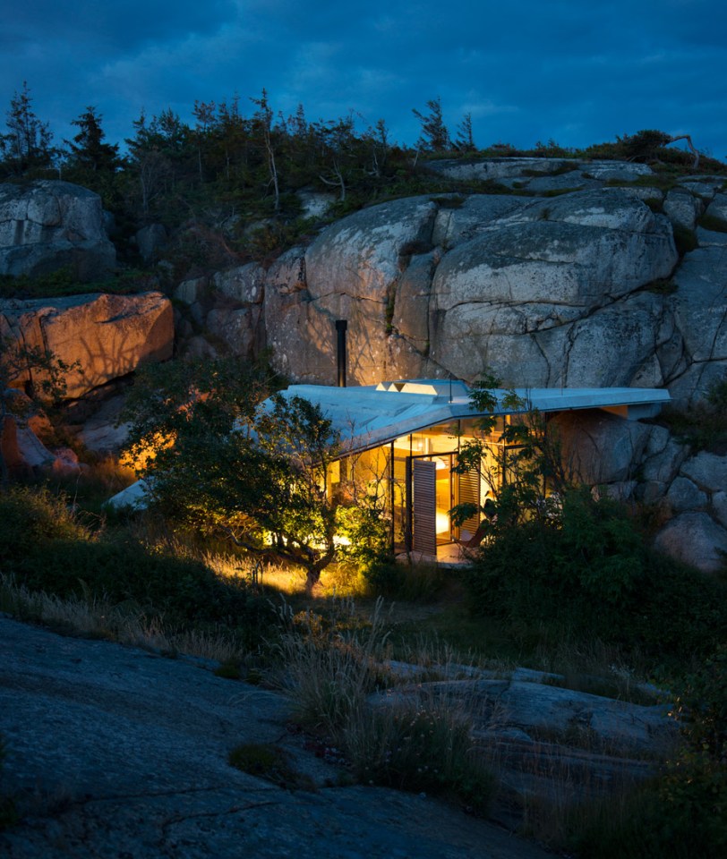 Half-hidden by dense vegetation, this modern cabin is tucked into a rocky Norwegian coastline. It is a 323 sq ft studio design with a sleeping loft suspended from the ceiling. | www.facebook.com/SmallHouseBliss