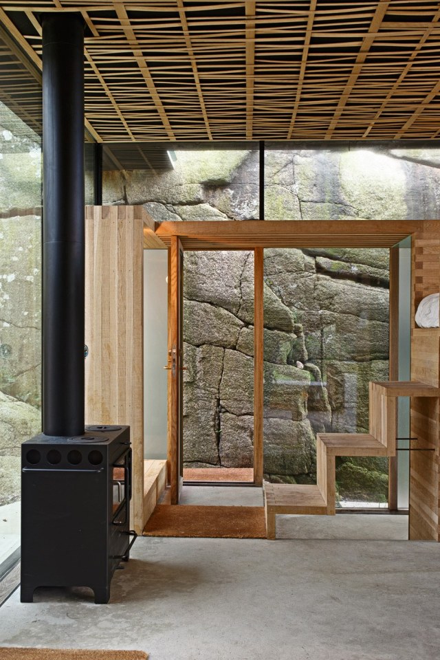 Half-hidden by dense vegetation, this modern cabin is tucked into a rocky Norwegian coastline. It is a 323 sq ft studio design with a sleeping loft suspended from the ceiling. | www.facebook.com/SmallHouseBliss